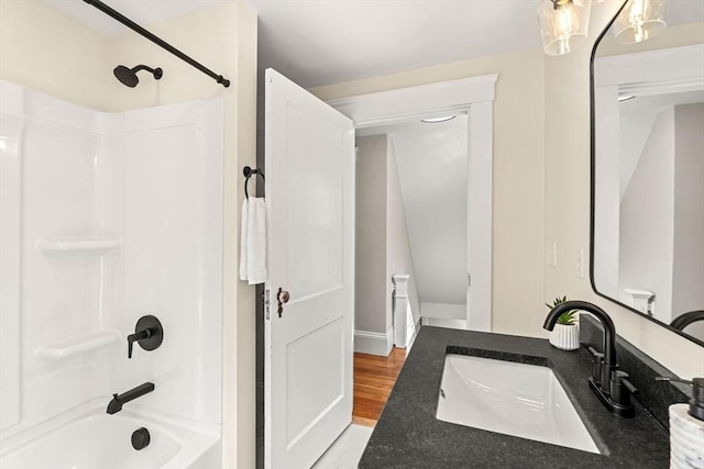 bathroom with wood finished floors, a sink, and bathtub / shower combination