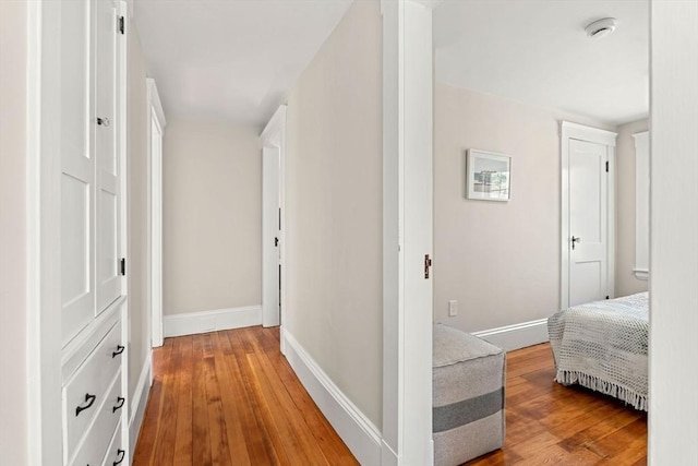 corridor featuring baseboards and light wood finished floors