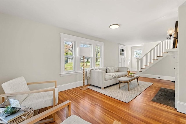 living area with baseboards, wood finished floors, and stairway