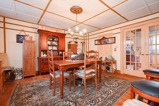 dining space with hardwood / wood-style floors, french doors, and a notable chandelier