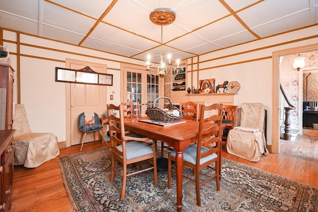 dining room with hardwood / wood-style flooring, french doors, and a chandelier