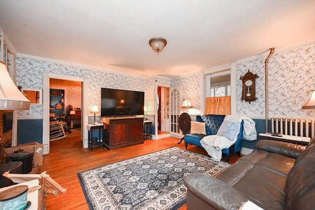 living room featuring wood-type flooring, radiator heating unit, and ornamental molding