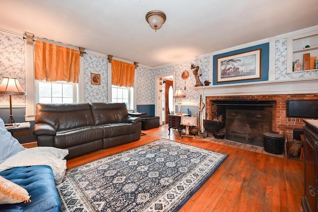 living room with crown molding, a fireplace, and wood-type flooring