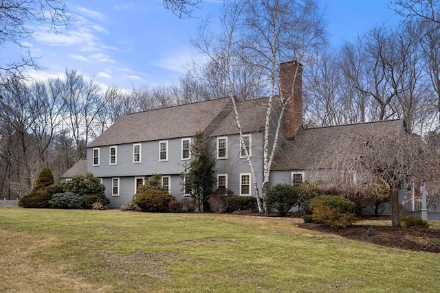 view of front facade featuring roof with shingles, a chimney, and a front yard