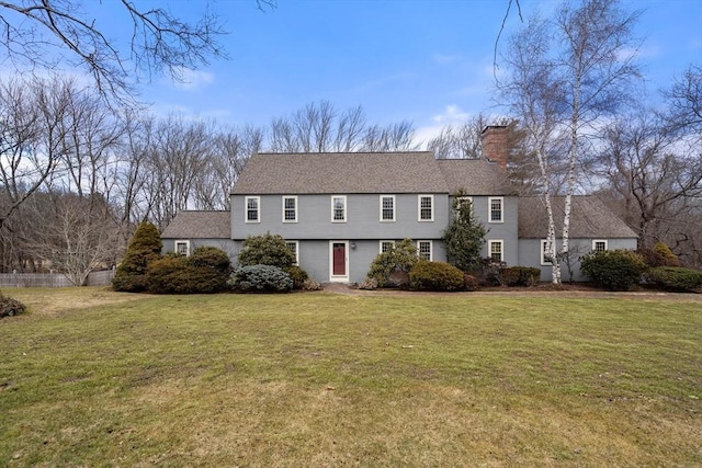 colonial inspired home with a chimney and a front yard