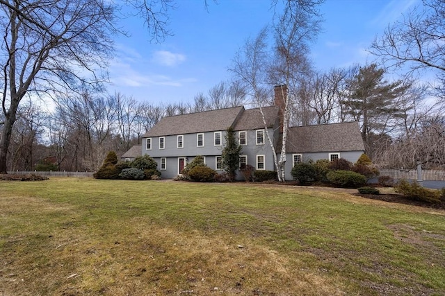 view of front of house featuring a chimney, a front lawn, and fence