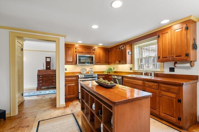 kitchen with light wood-style flooring, a sink, a kitchen island, recessed lighting, and appliances with stainless steel finishes