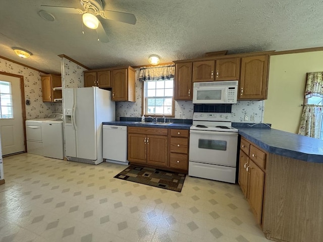 kitchen with brown cabinetry, crown molding, white appliances, wallpapered walls, and washing machine and clothes dryer