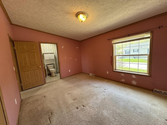carpeted empty room featuring visible vents, ornamental molding, a textured ceiling, and lofted ceiling