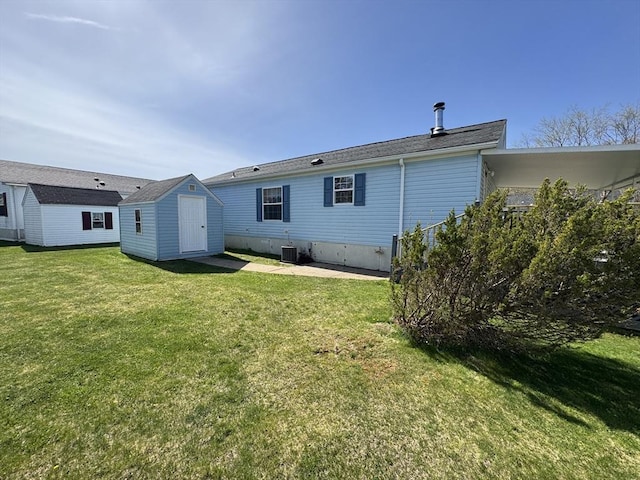 back of house with a storage unit, an outdoor structure, a lawn, and central AC unit