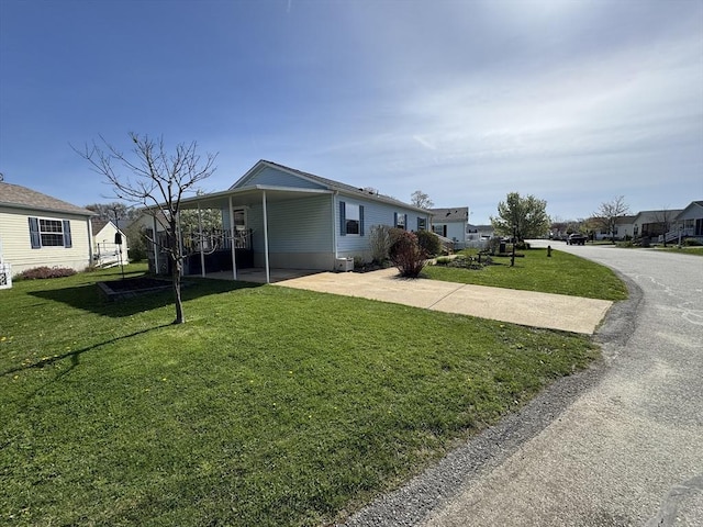 view of front of property featuring concrete driveway, a carport, and a front lawn