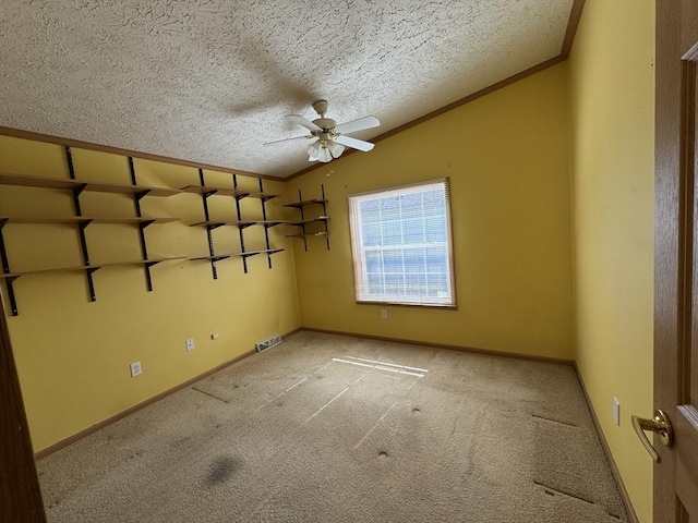 unfurnished room featuring ornamental molding, light carpet, a textured ceiling, a ceiling fan, and vaulted ceiling