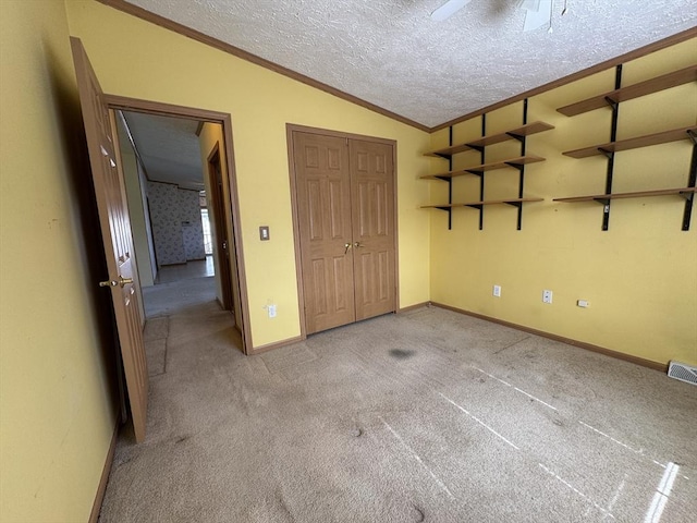 unfurnished bedroom featuring crown molding, baseboards, light colored carpet, a textured ceiling, and vaulted ceiling