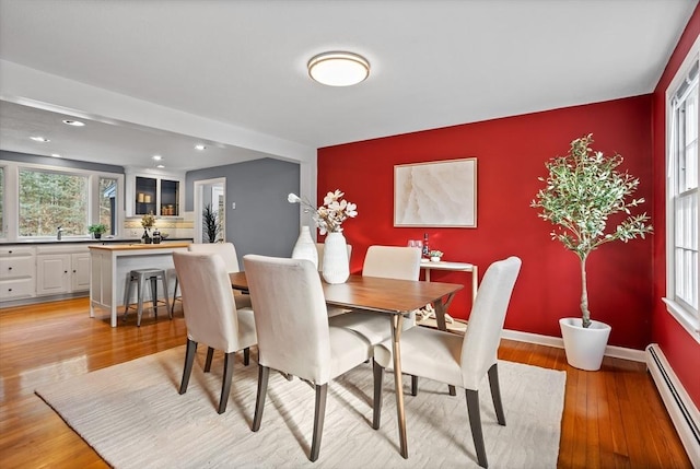 dining room with light wood-type flooring, sink, and a baseboard heating unit