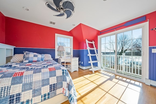 bedroom with multiple windows, wood-type flooring, and ceiling fan