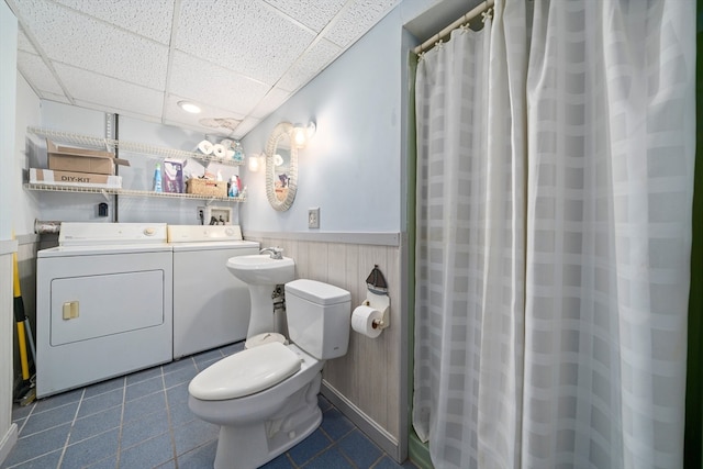 bathroom with a paneled ceiling, toilet, and washing machine and clothes dryer