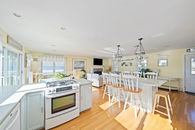 kitchen featuring light wood-type flooring, pendant lighting, a healthy amount of sunlight, and a kitchen breakfast bar