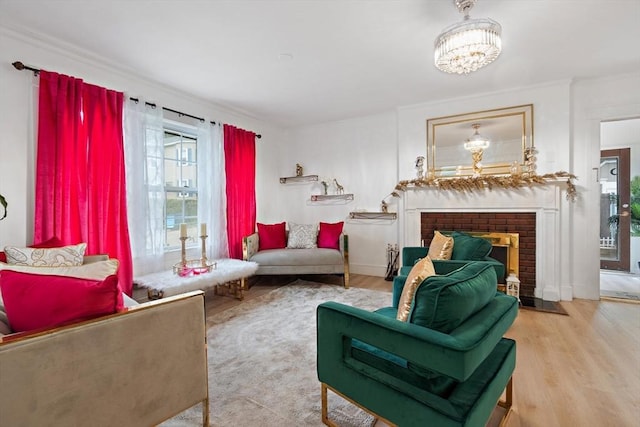 living area with a chandelier, light hardwood / wood-style floors, a fireplace, and crown molding