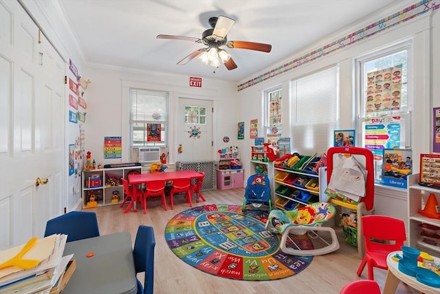 recreation room with ceiling fan, ornamental molding, a healthy amount of sunlight, and light hardwood / wood-style floors