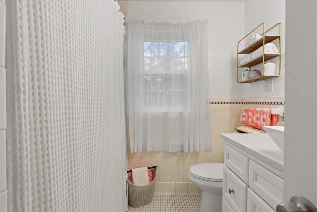 bathroom with tile patterned floors, vanity, toilet, and tile walls