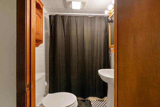 bathroom featuring a shower with curtain, tile walls, and toilet