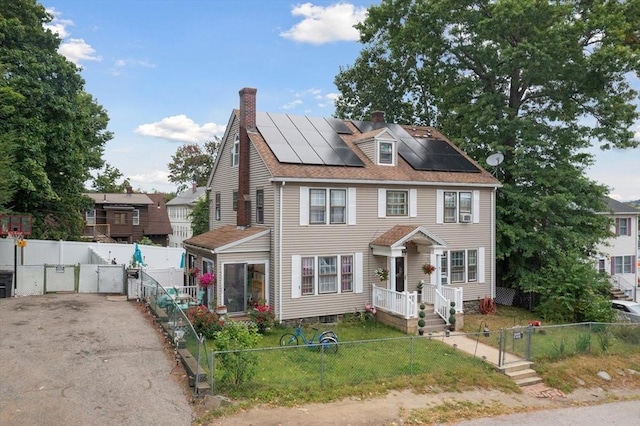 colonial house featuring solar panels and a front lawn