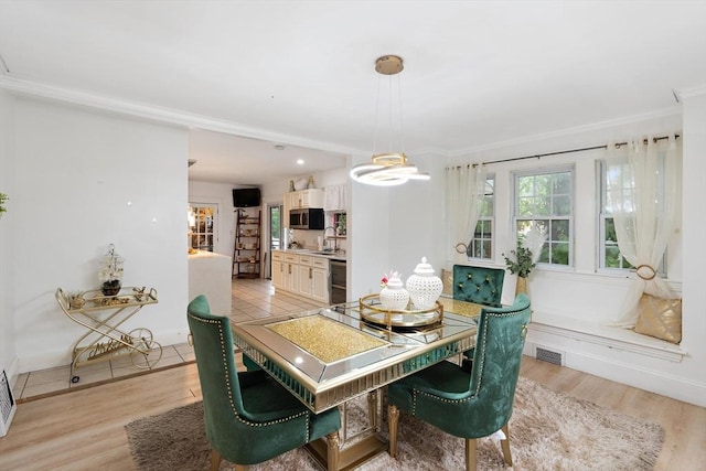 dining room with light hardwood / wood-style flooring, a notable chandelier, crown molding, and sink