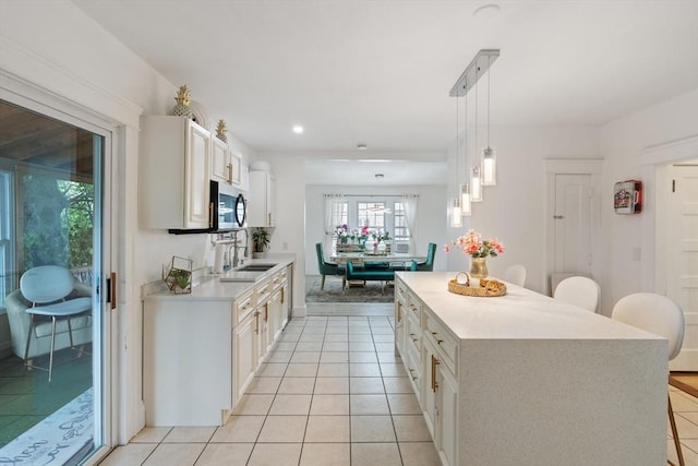 kitchen featuring a kitchen breakfast bar, sink, light tile patterned flooring, and hanging light fixtures