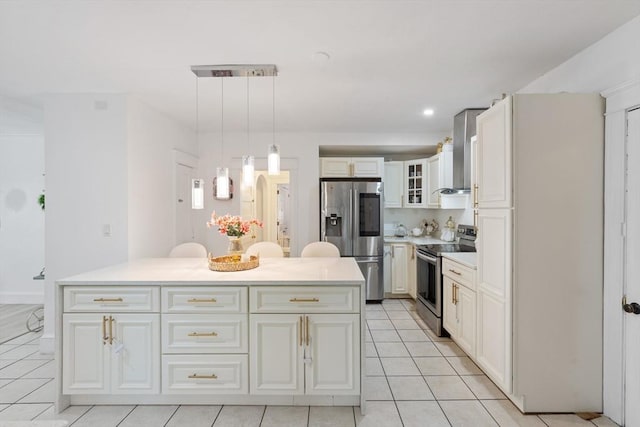 kitchen with appliances with stainless steel finishes, wall chimney range hood, light tile patterned floors, pendant lighting, and a center island