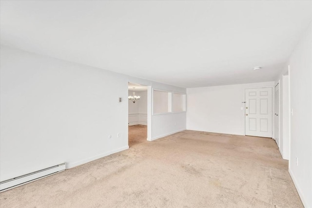 carpeted empty room featuring a baseboard heating unit and a chandelier