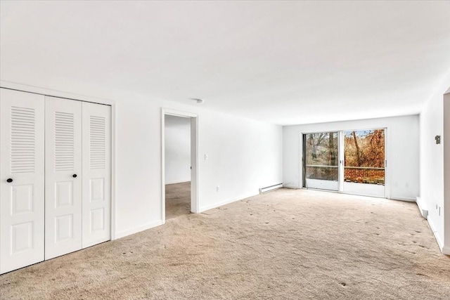 unfurnished living room featuring carpet flooring and a baseboard heating unit