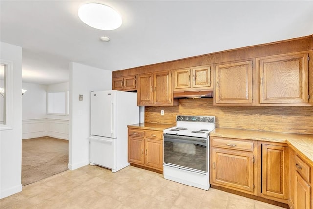 kitchen with white appliances, backsplash, and light carpet