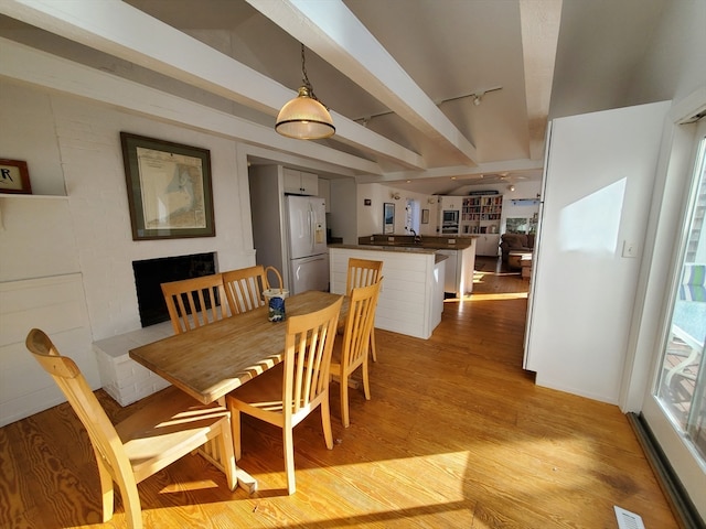 dining space with beamed ceiling and light wood-type flooring