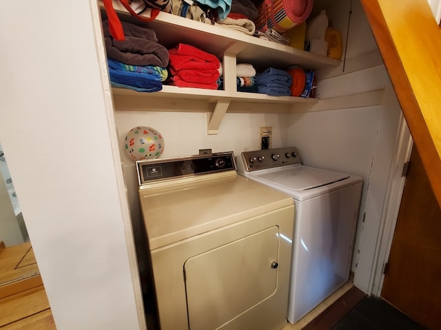 clothes washing area with wood-type flooring and separate washer and dryer