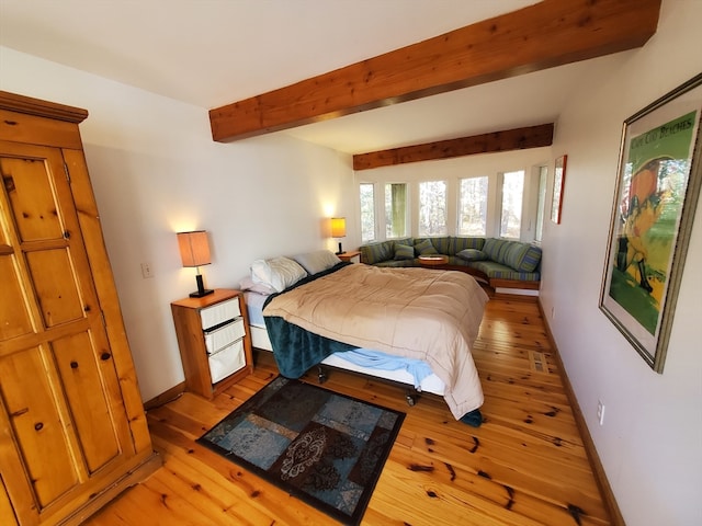 bedroom with beam ceiling and light hardwood / wood-style floors