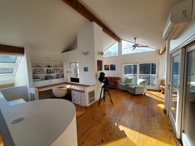 interior space with built in desk, an AC wall unit, high vaulted ceiling, beamed ceiling, and light hardwood / wood-style floors