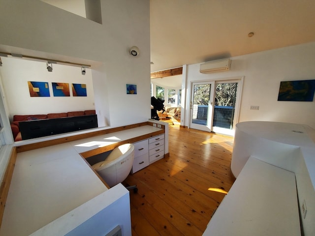 living room featuring wood-type flooring, a high ceiling, and a wall mounted AC