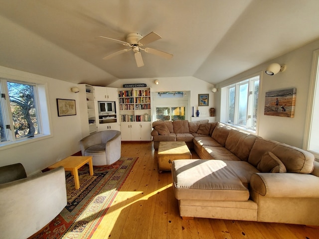 living room with a healthy amount of sunlight, light hardwood / wood-style floors, ceiling fan, and lofted ceiling