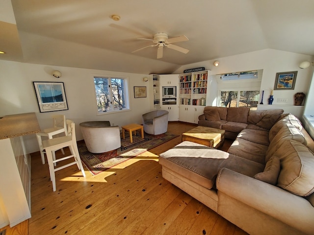 living room featuring a wealth of natural light, wood-type flooring, and vaulted ceiling