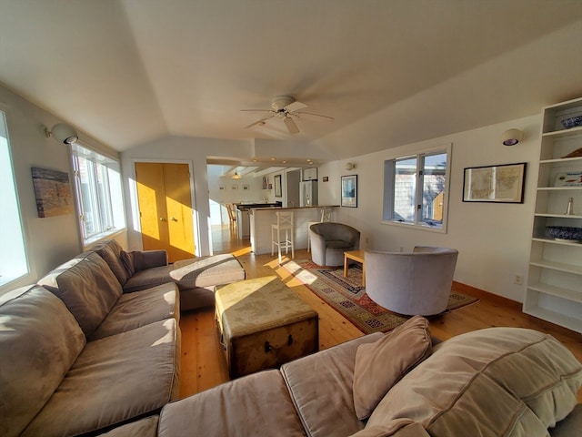 living room featuring ceiling fan, light hardwood / wood-style floors, and lofted ceiling