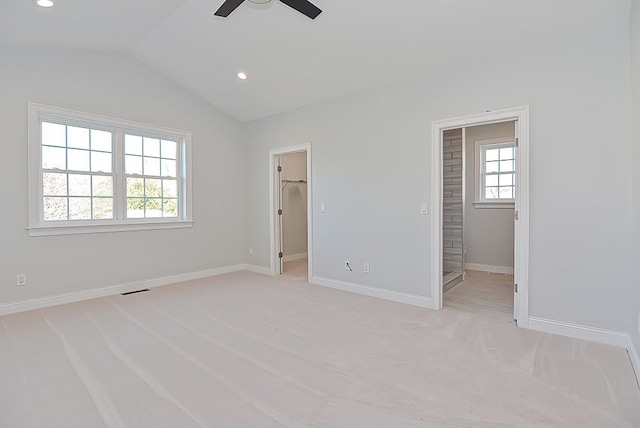 unfurnished bedroom with vaulted ceiling, multiple windows, carpet floors, and a walk in closet