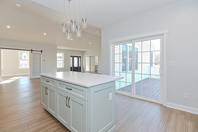 kitchen with a healthy amount of sunlight, light hardwood / wood-style floors, a barn door, and decorative light fixtures