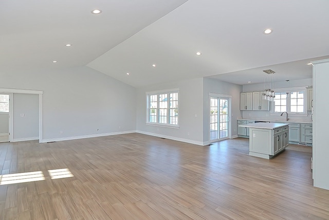 unfurnished living room featuring sink, light hardwood / wood-style flooring, and lofted ceiling