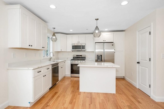 kitchen featuring light hardwood / wood-style flooring, hanging light fixtures, and appliances with stainless steel finishes