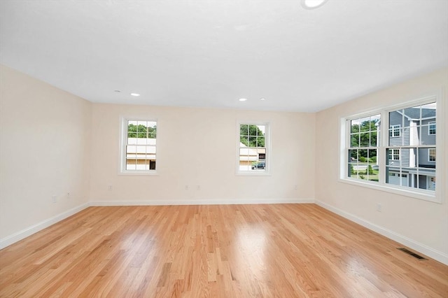 empty room with a healthy amount of sunlight and light hardwood / wood-style floors