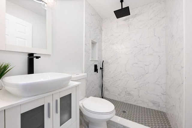 bathroom with vanity, toilet, and a tile shower