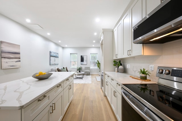 kitchen featuring white cabinetry, stainless steel appliances, light wood-type flooring, light stone counters, and backsplash