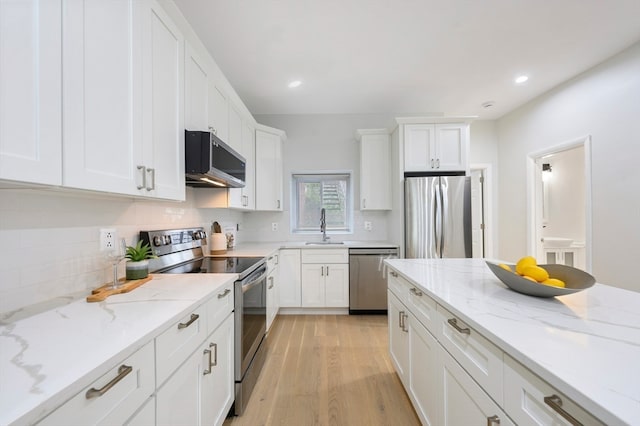 kitchen with light wood-type flooring, light stone countertops, appliances with stainless steel finishes, decorative backsplash, and sink