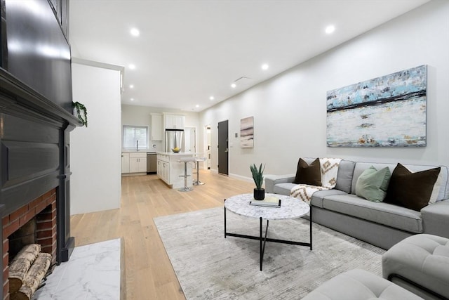 living room with sink, a fireplace, and light hardwood / wood-style floors