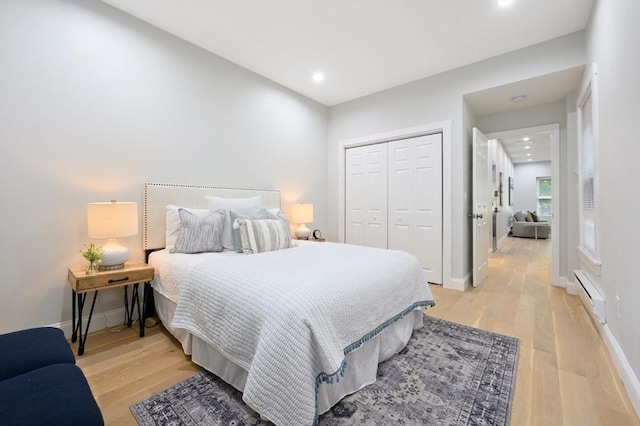 bedroom with light hardwood / wood-style flooring, a closet, and a baseboard heating unit